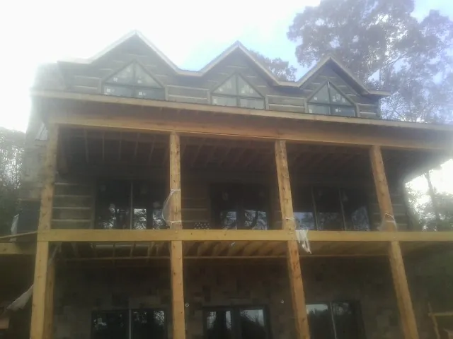 Dormers and porch framing on a large log home under construction — Roof Coating work by our crew in Orient
