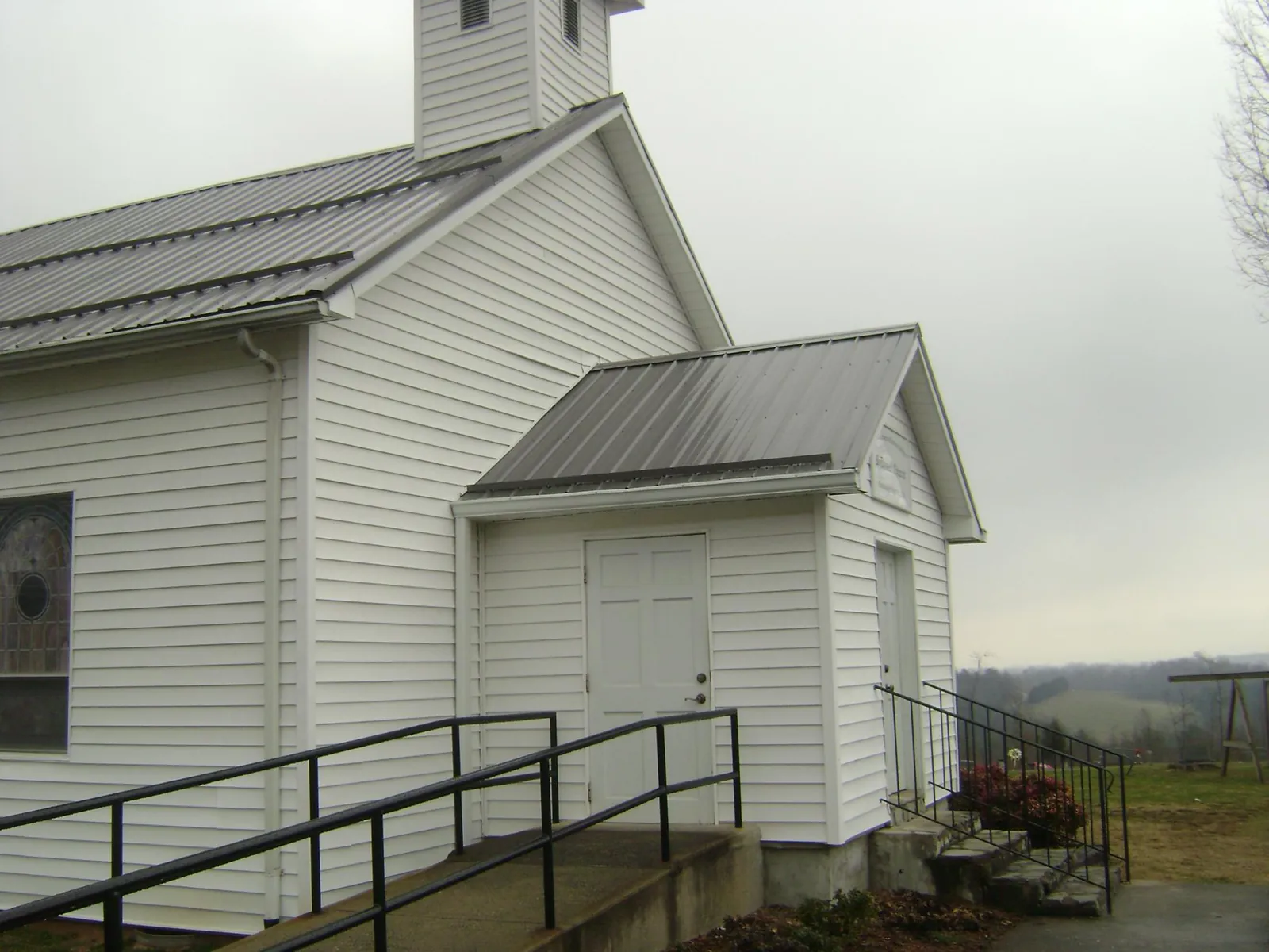 Gray metal roof on a white clapboard church with a steeple in Orient